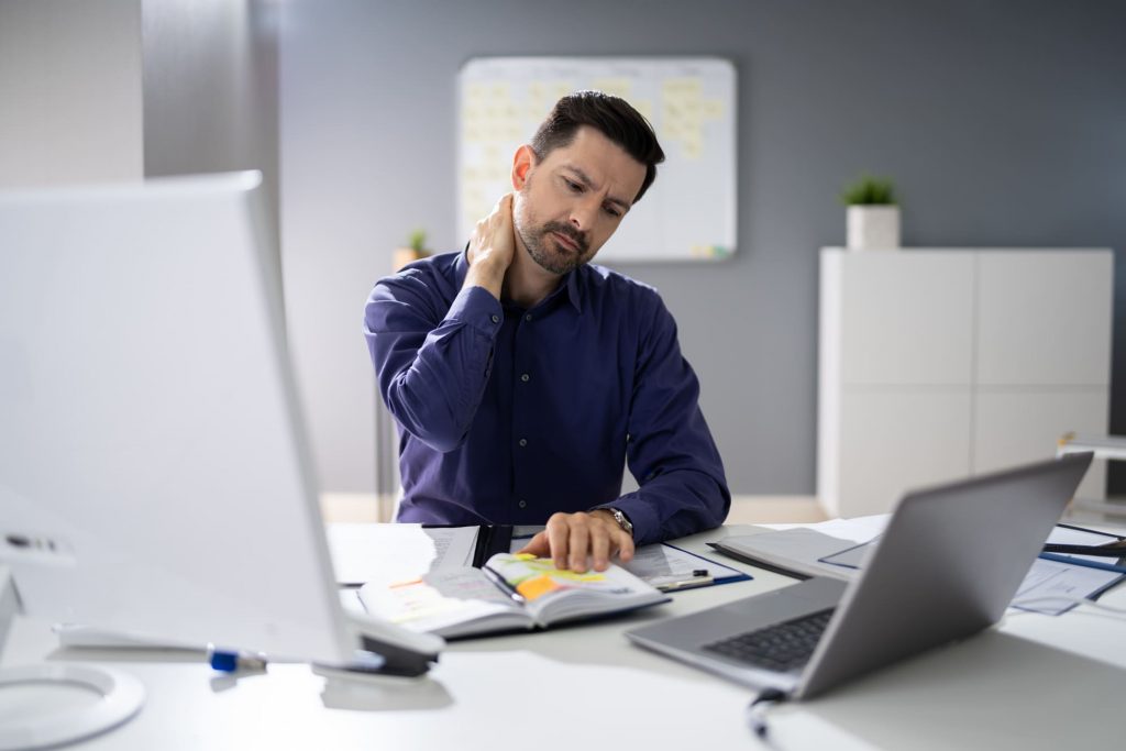 man holding neck sitting at desk