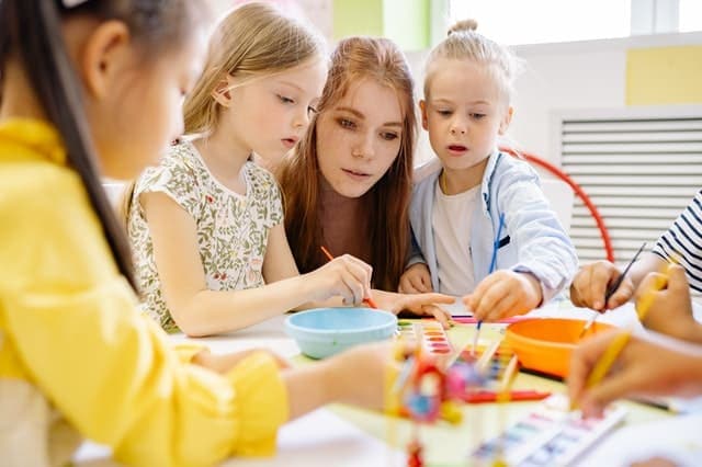 children learning with female teacher at desk