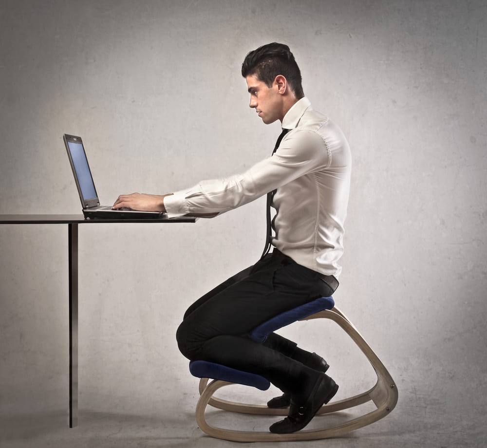 man in kneeling chair in front of desk